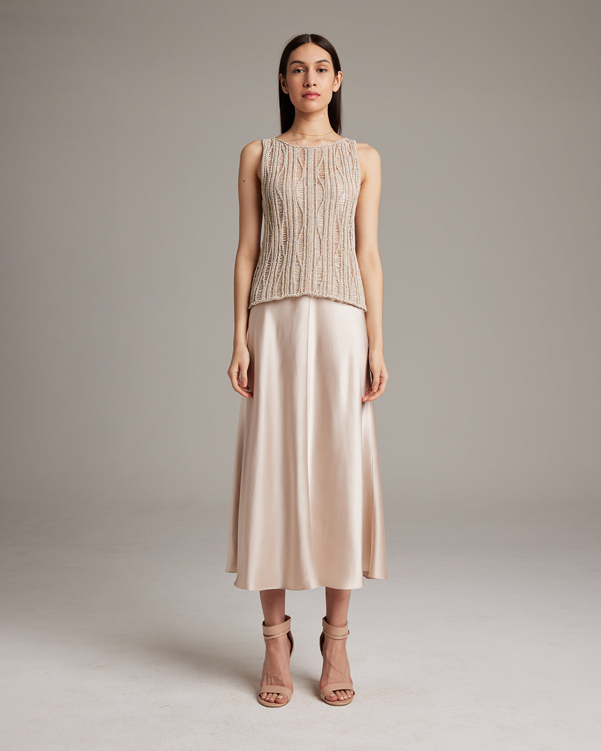 Model wearing a lace knit tank top with a skirt and heels