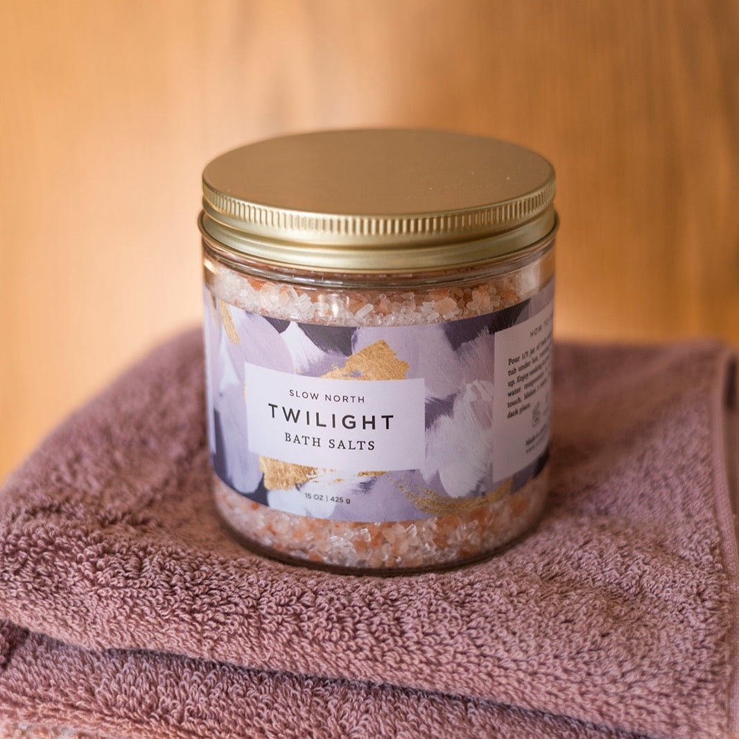 jar containing pink and purple crystals on stack of purple towels