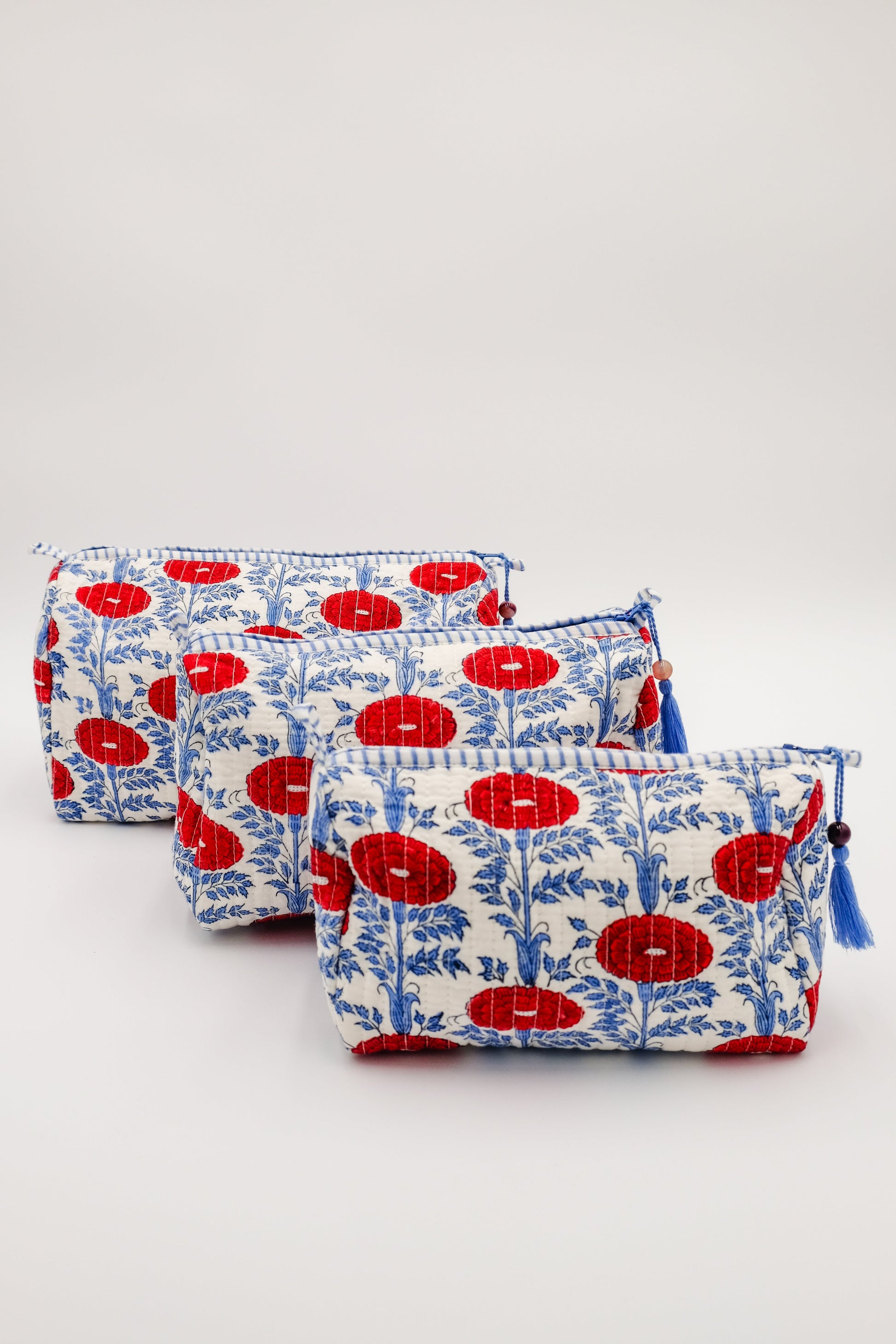 Three toiletry bags with red floral patterns arranged from Inner Child