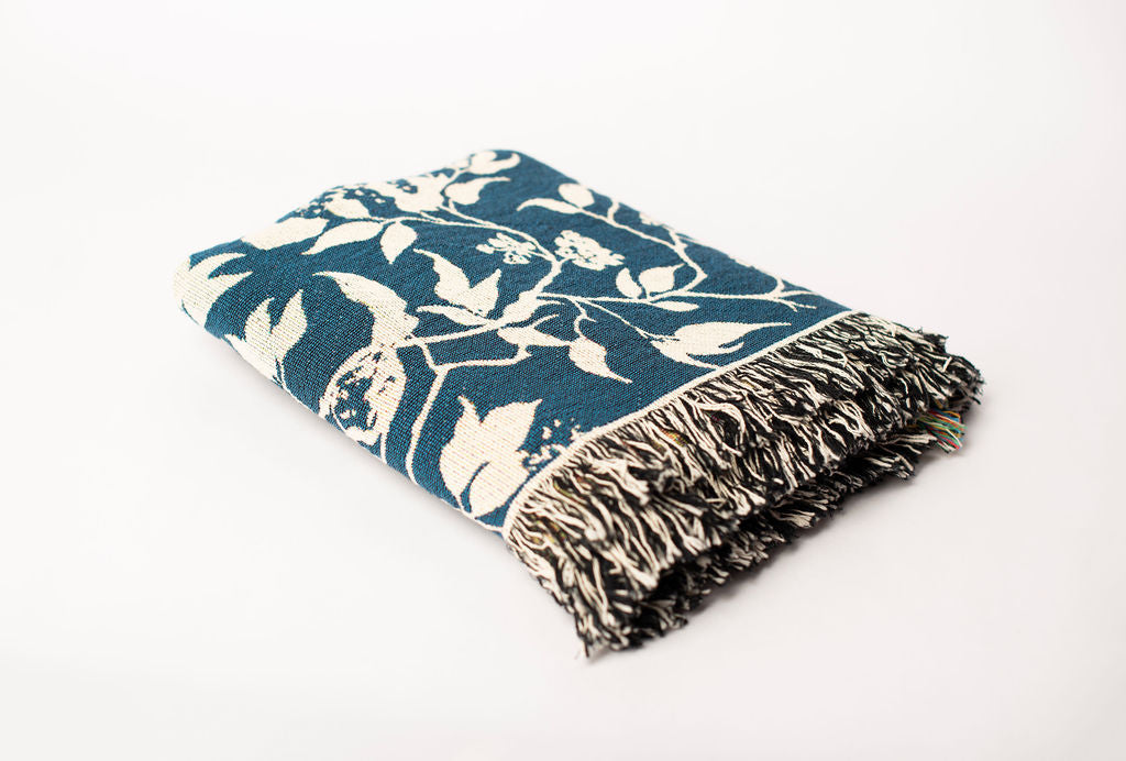 Folded Wren Tidesong bird and botanical woven throw blanket shown from the side
