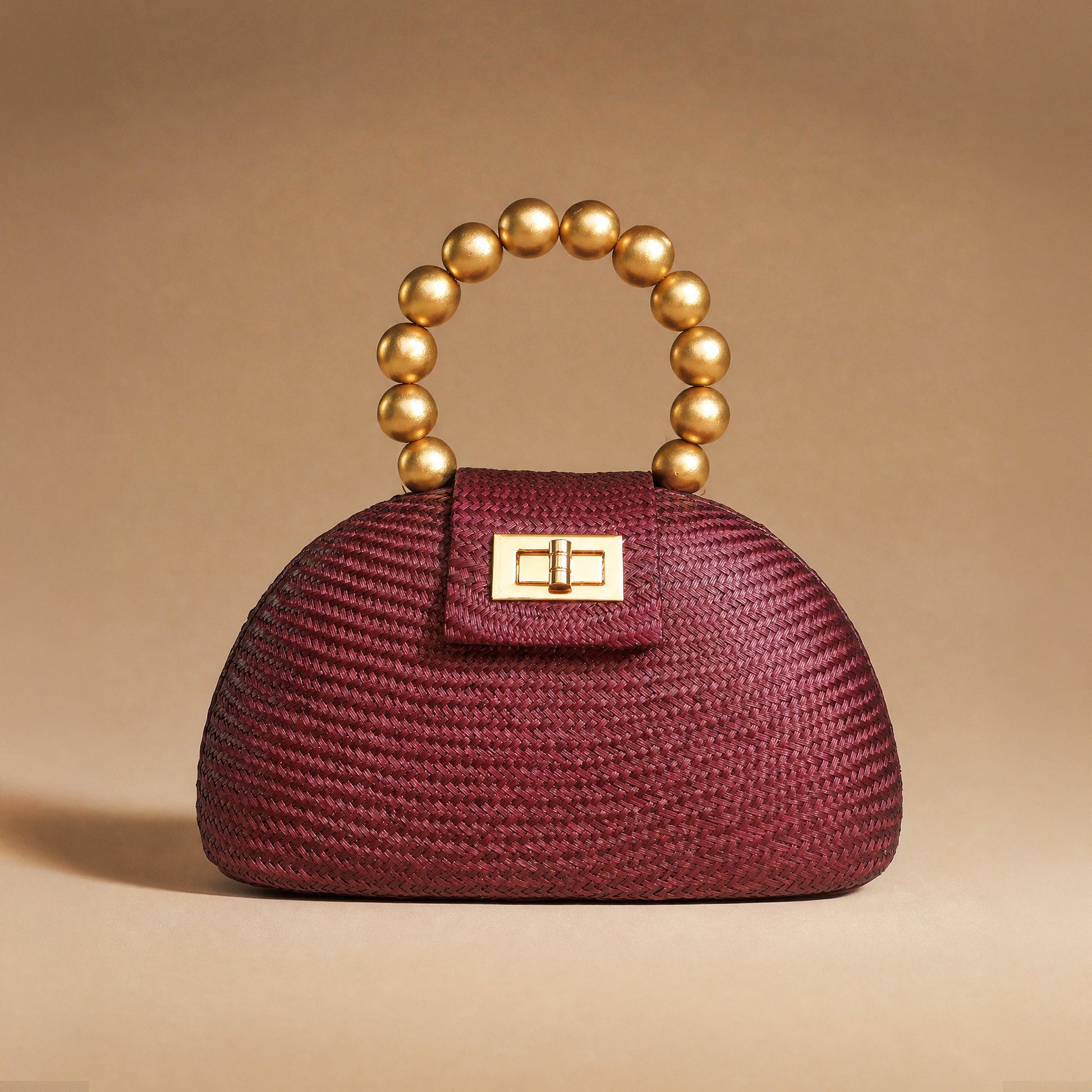 The Orla in maroon buntal straw styled against a warm backdrop