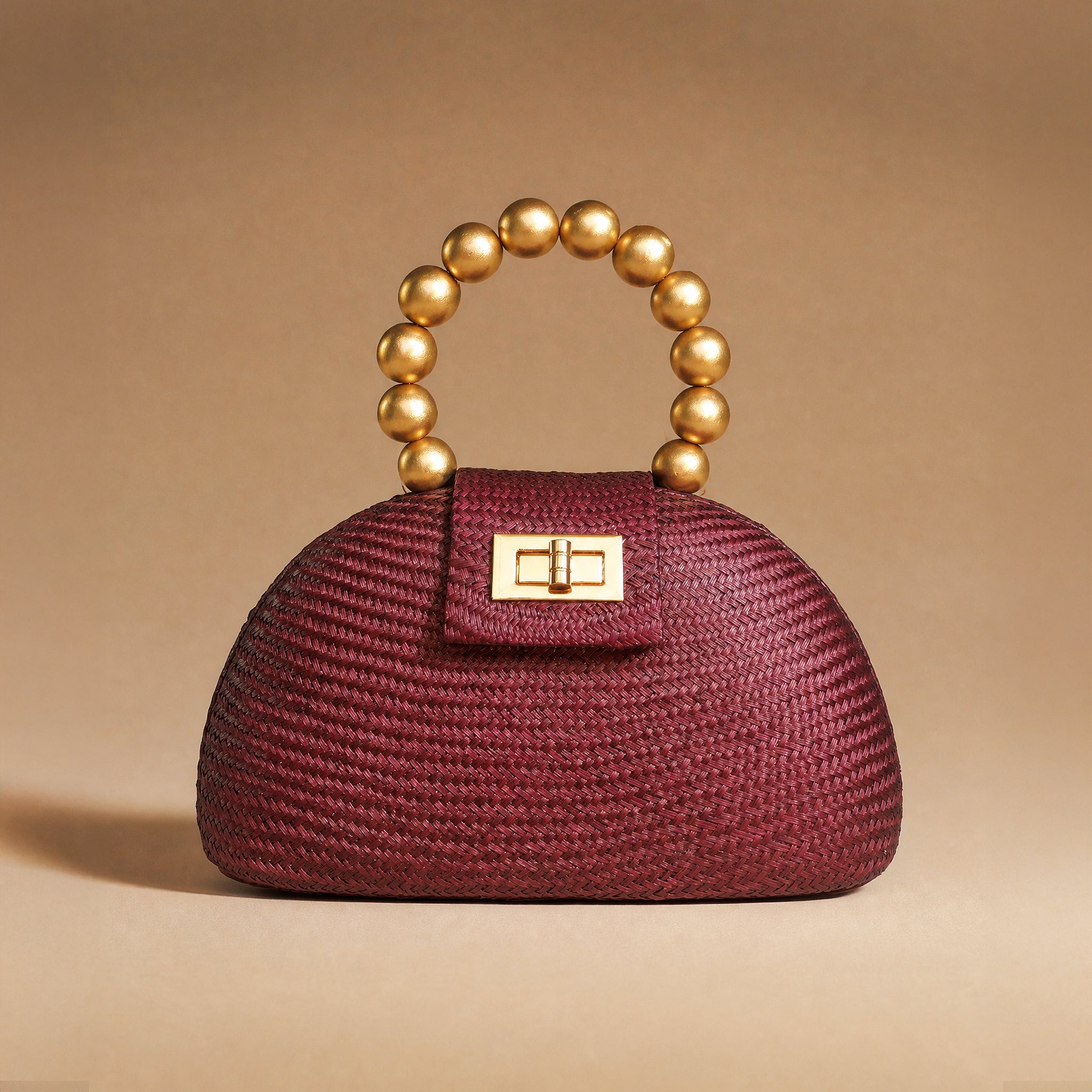 The Orla in maroon buntal straw styled against a warm backdrop