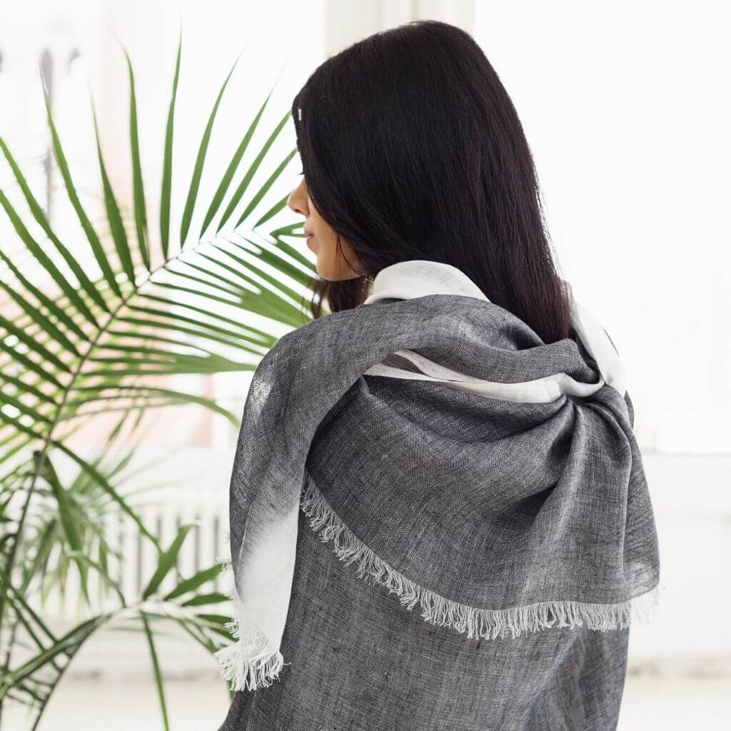 Person wearing a Granite Black White Ombre Linen Silk Handloom Scarf, showcasing its elegant design and texture.