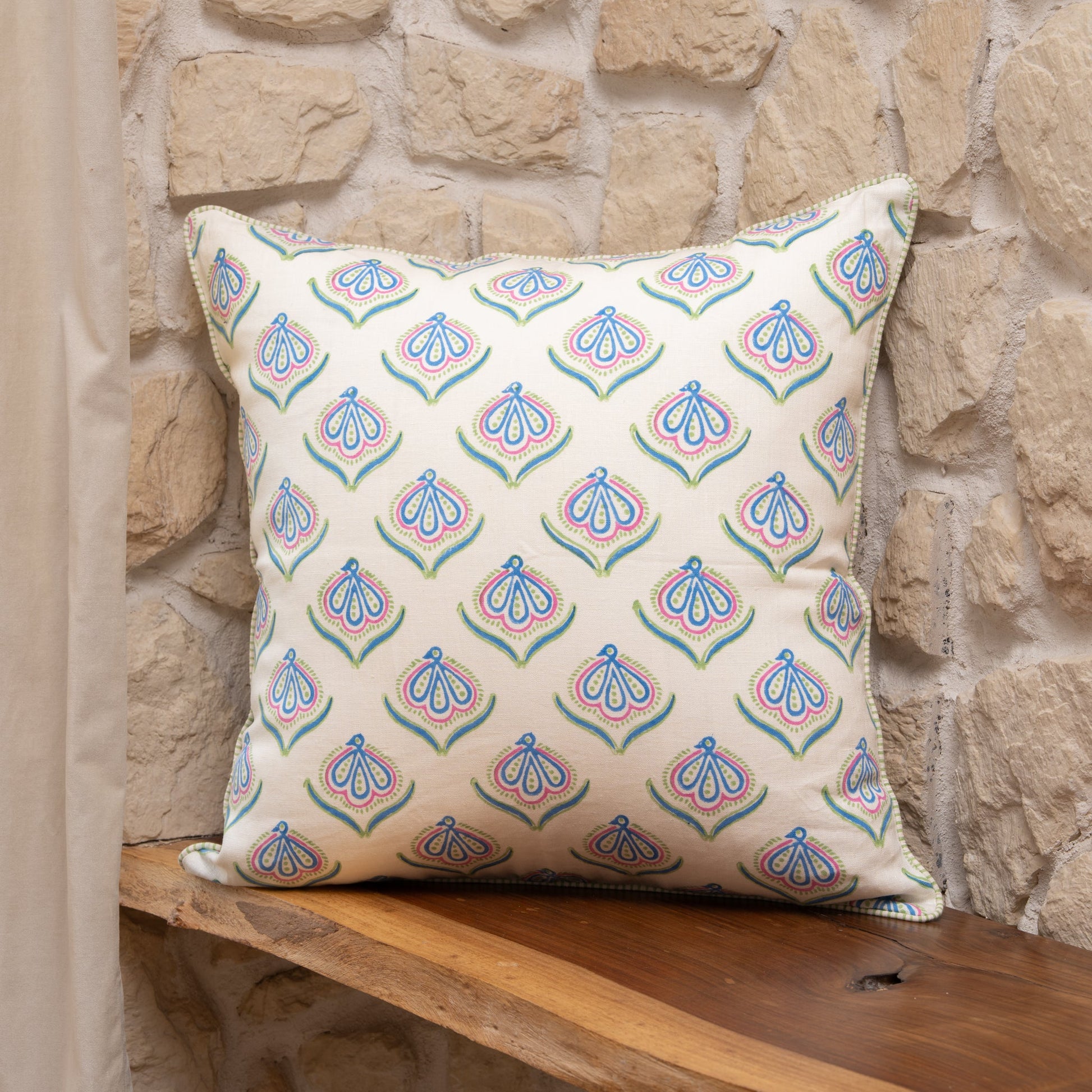 Hand block printed linen pillow cover with delicate bird print in soft blue, green and pink  natural dyes on a stone wall background
