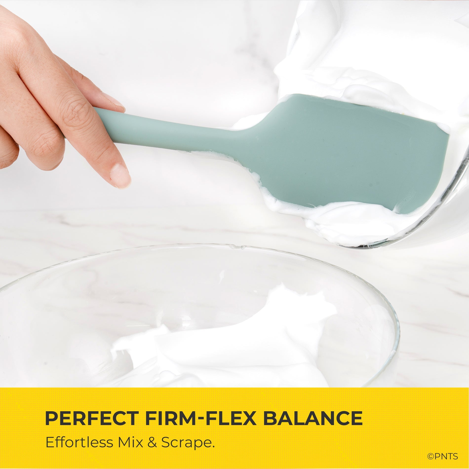 Silicone spatula being used to mix a white substance in a clear bowl with text about firm-flex balance.