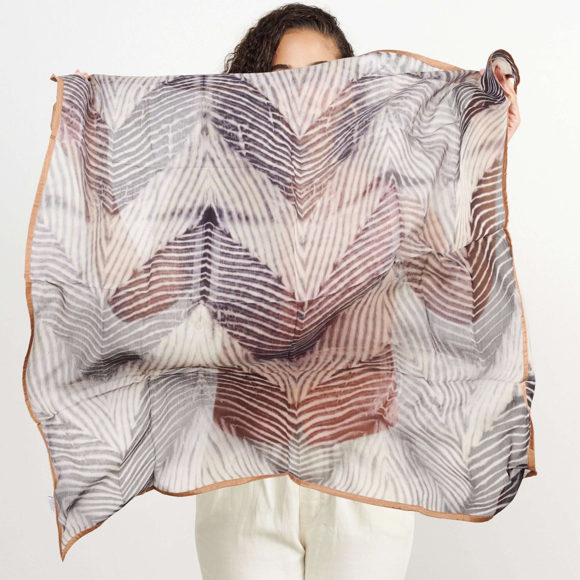 Samu Black hand crafted shibori print silk chiffon square scarf held up by a model, showcasing its elegant design.
