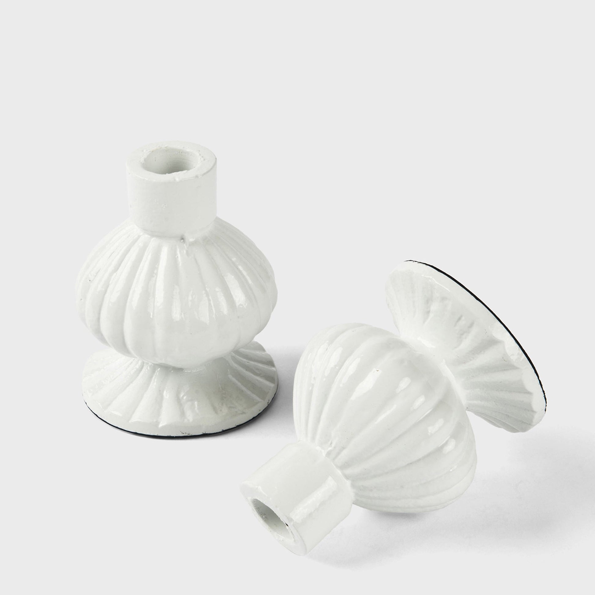 Two white ceramic candle holders on a light gray background