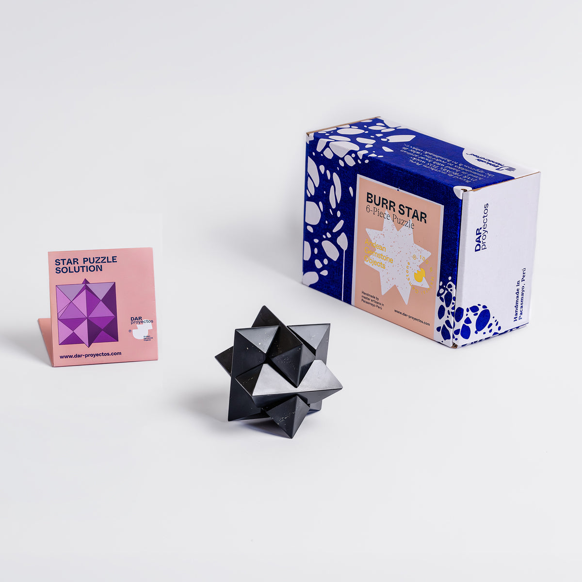 Angled view of the assembled black onyx burr star puzzle on a white background.