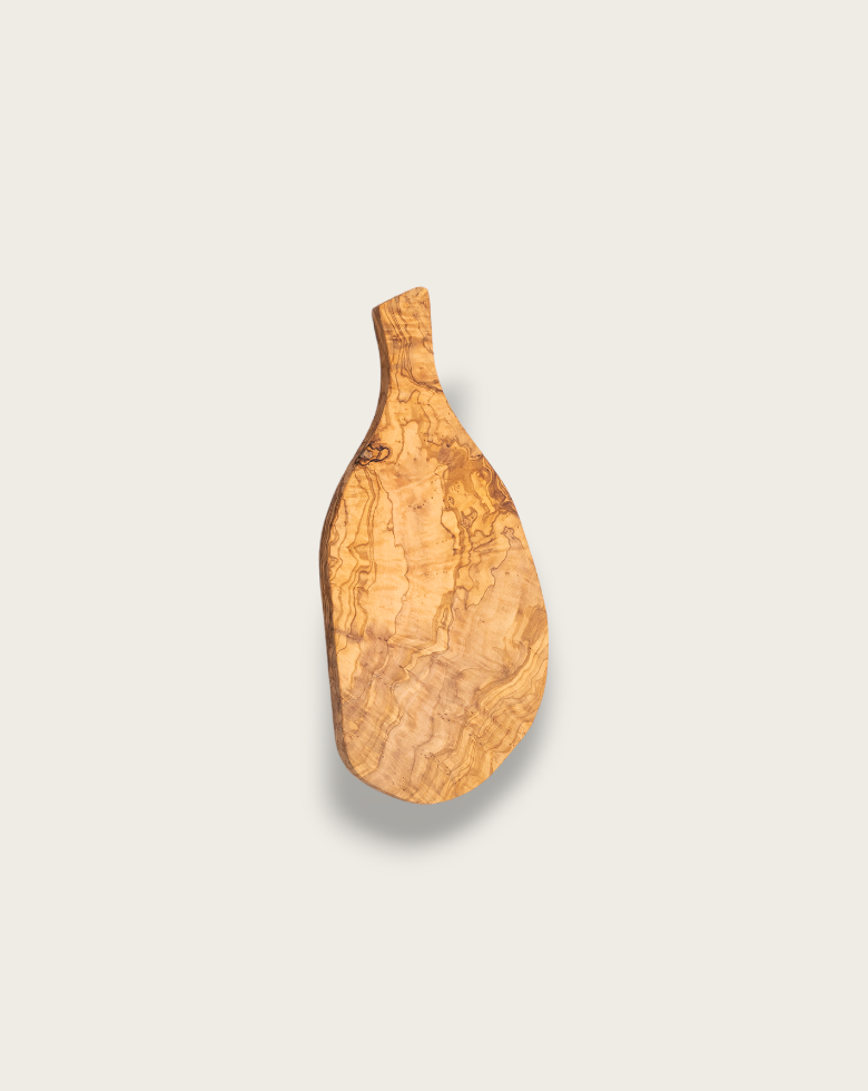A plain natural olive wood cheese board with an organic shape and handle, displayed against a white background to highlight its grain and form.
