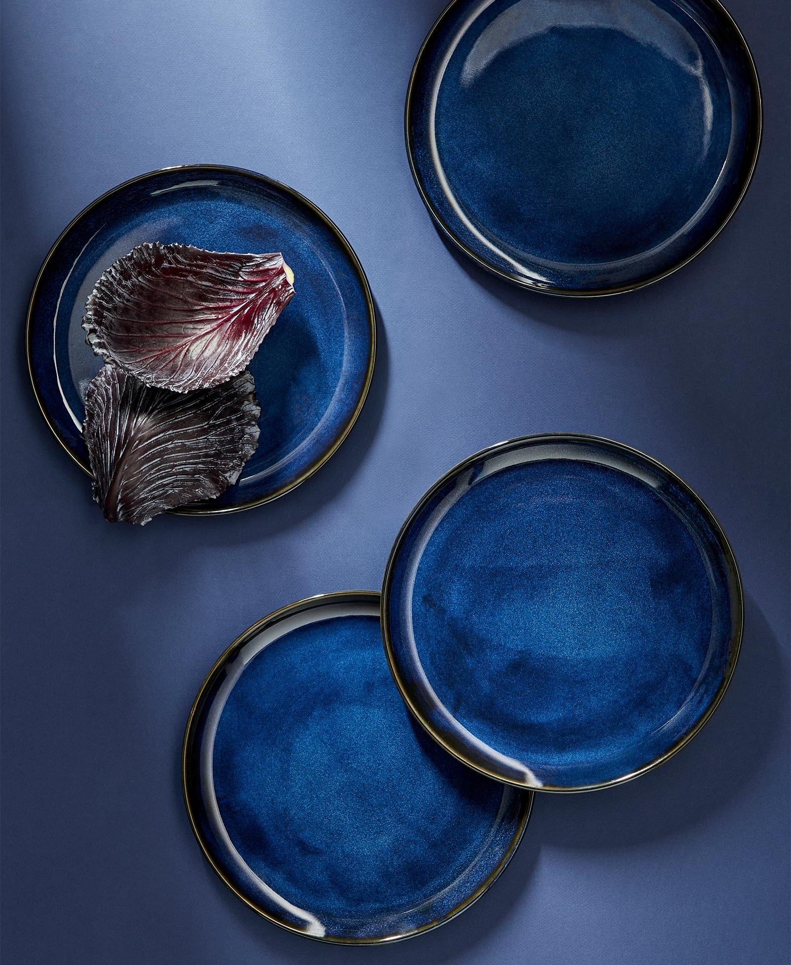 Two stoneware flat plates with a matte finish, one with a plain beige surface and the other with a beige edge and white interior.