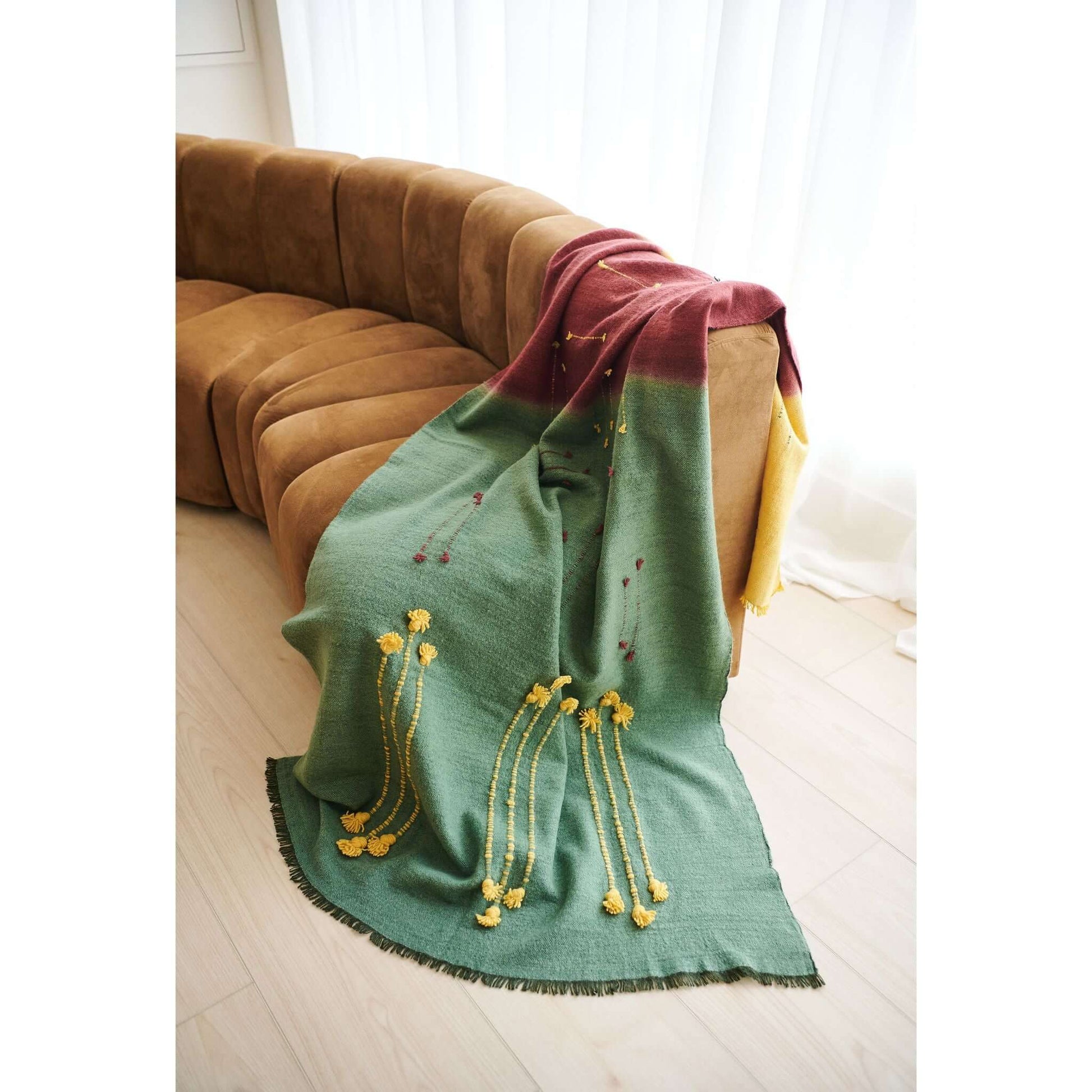 Avocado Green Multi Color Warm Hues Hand Woven Hand Knotted Textured Merino Throw draped on a modern couch.