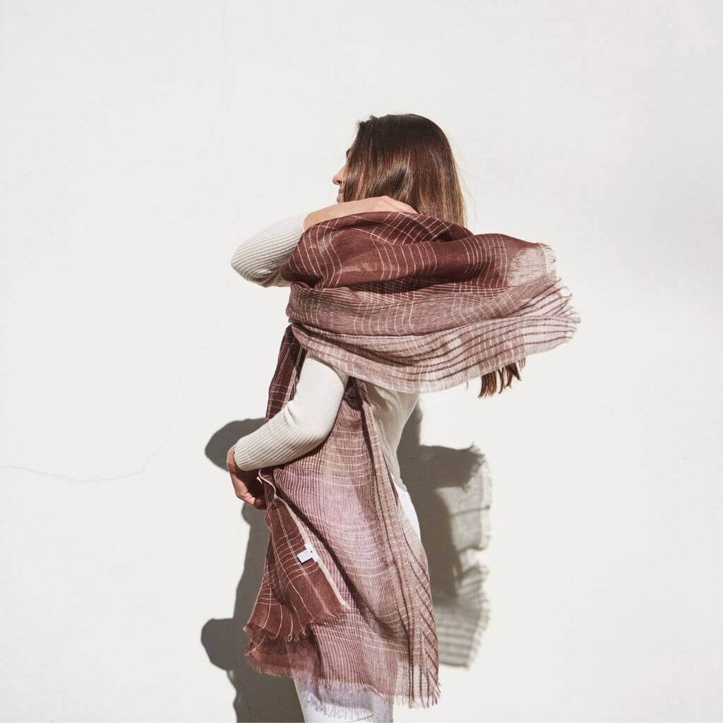 Auro Cinnabar Handwoven Earthy Rust Maroon Linen Scarf elegantly draped on a model against a white wall.