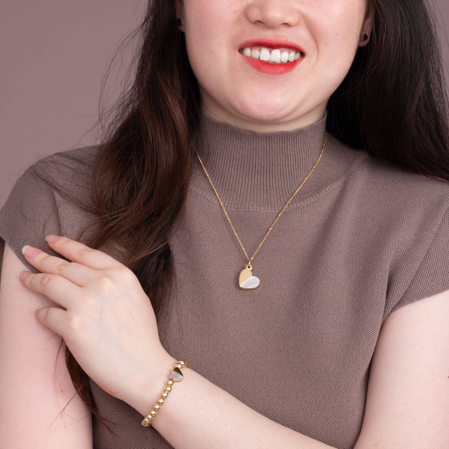 Woman wearing matching heart pendant necklace and bracelet, heart shaped jewelry, women's gold heart jewelry