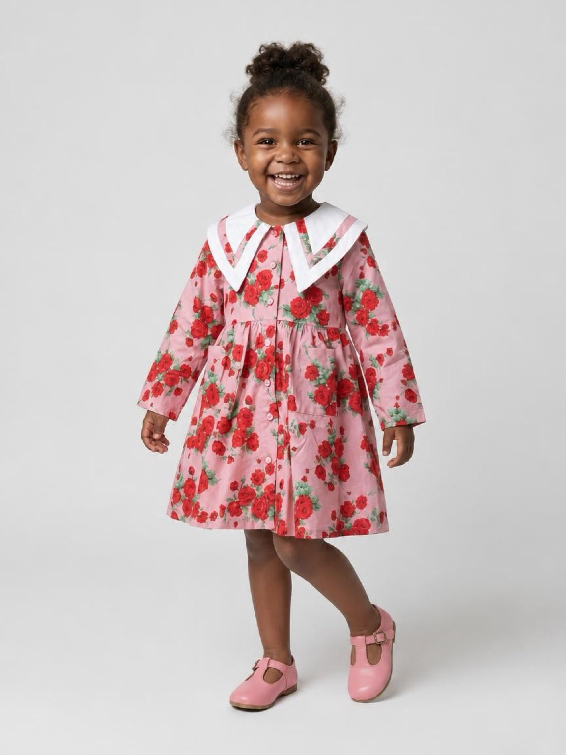 Child wearing a pink floral dress with a white collar on a white background