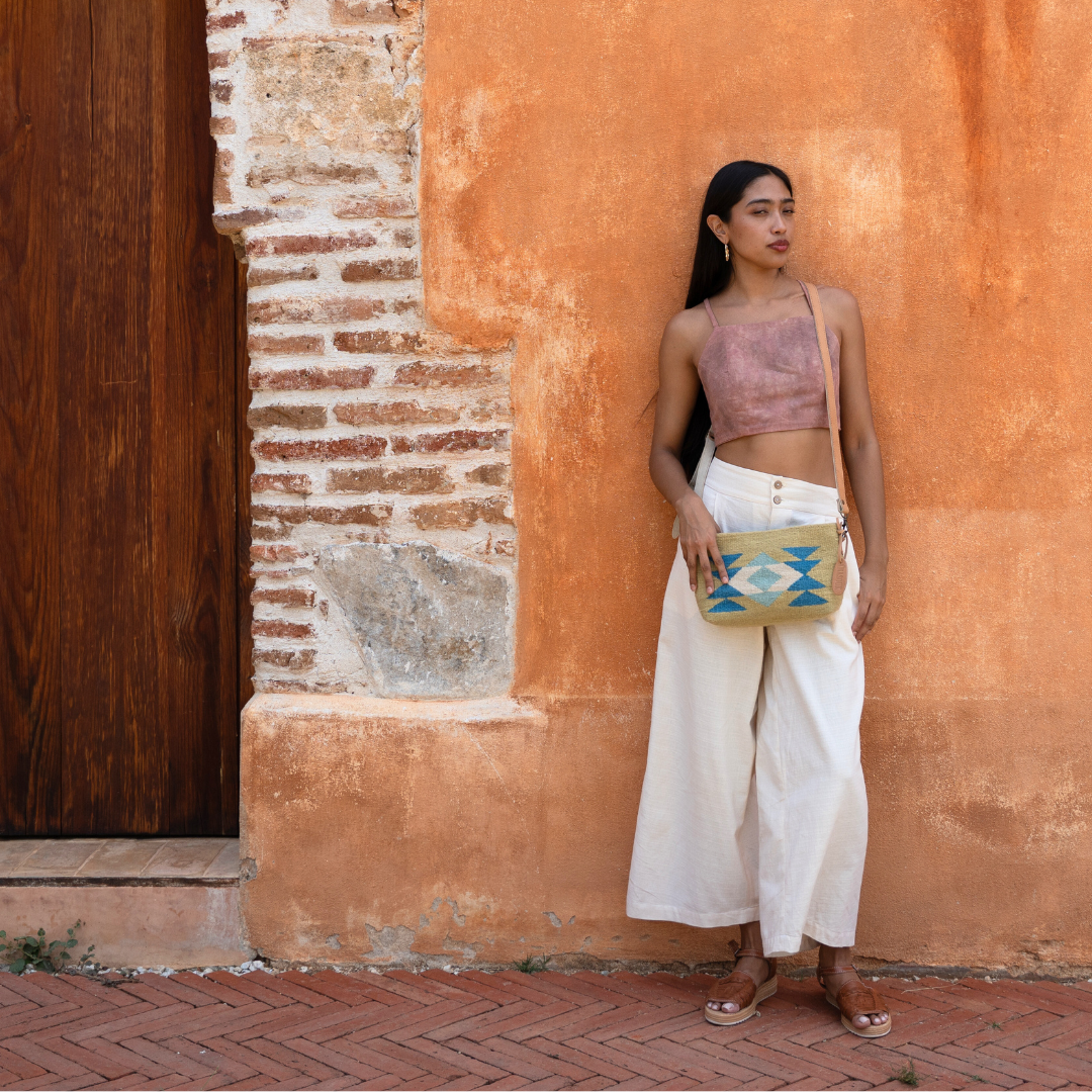 Woman wearing the handwoven convertible clutch with Zapotec butterfly design in bright spring colors; can be used as a pouch, wristlet, or crossbody with included leather straps and internal pocket