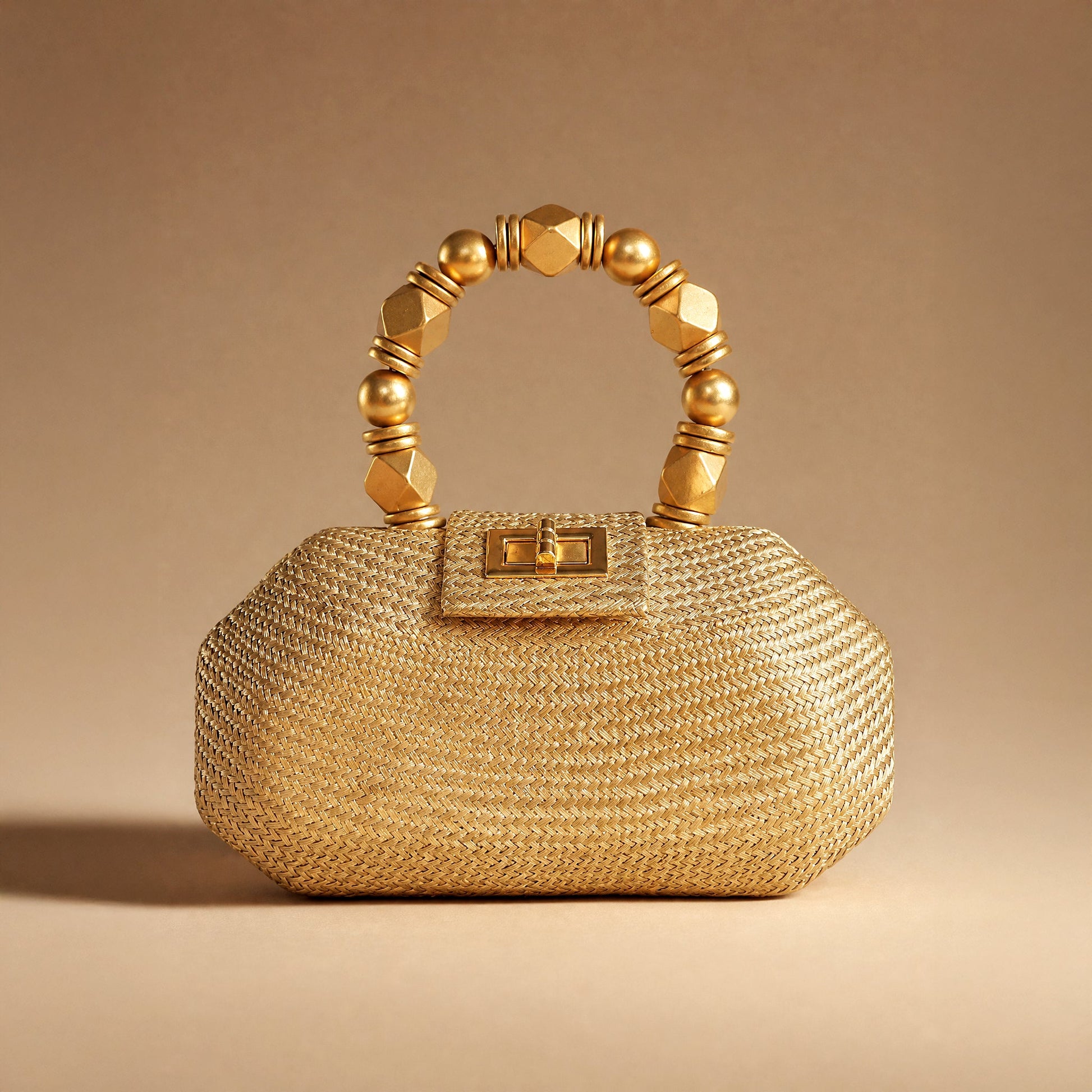 The Melia gold woven straw occasion bag styled against a warm gold backdrop
