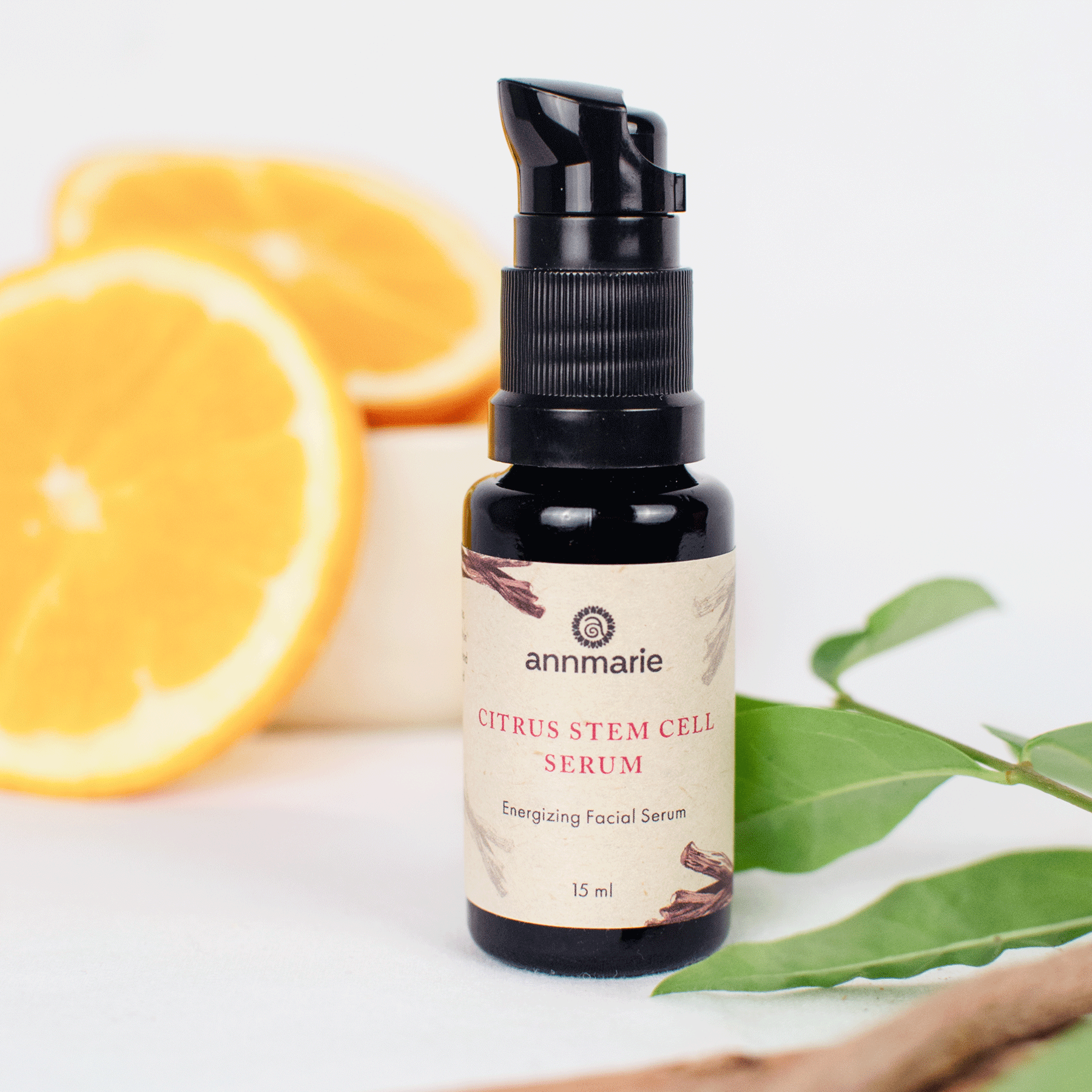 Citrus Stem Cell Serum energizing facial serum bottle styled with fresh orange slices and green leaves in the background.