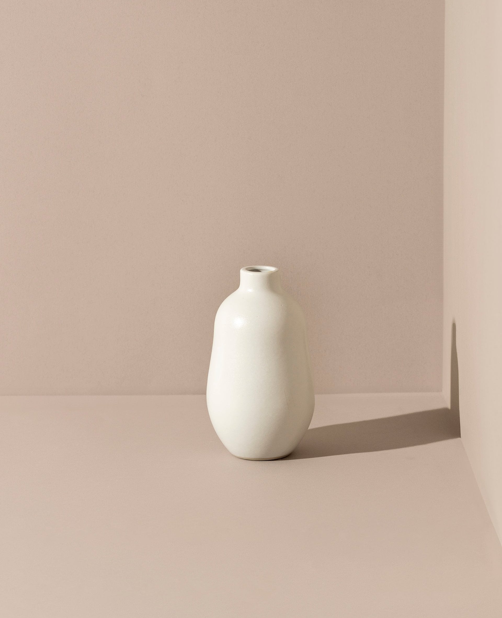 White handmade stoneware vase with a matte finish and minimalistic design, set against a soft cream-toned background for a warm, natural look.