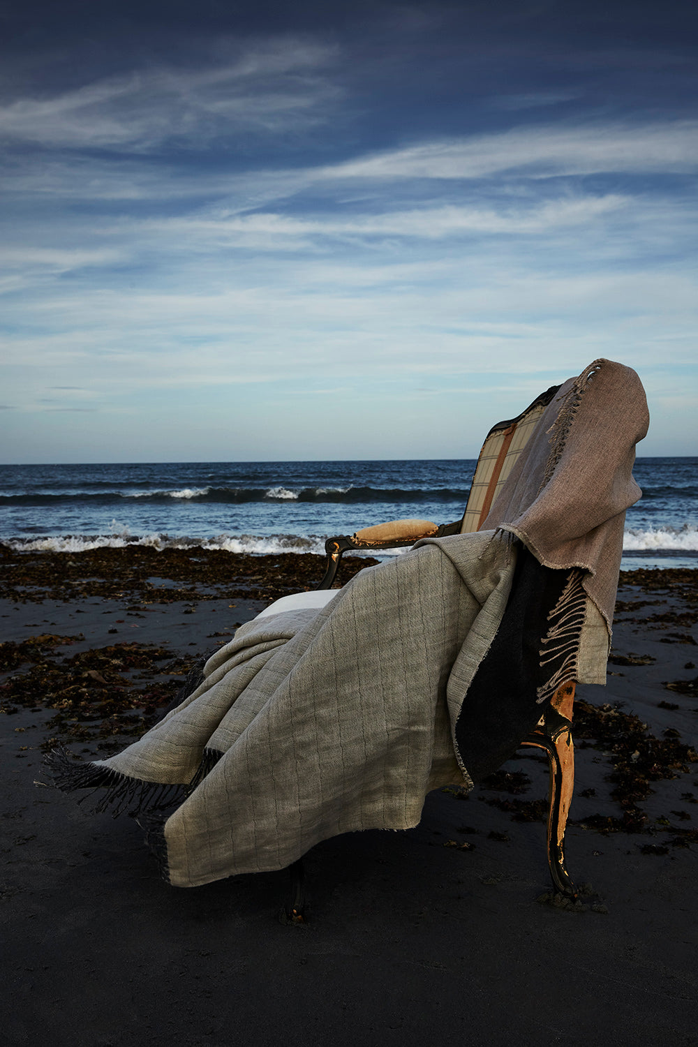 Evangeline Linens' luxurious linen and merino wool throw blanket gracefully placed on a couch on the beach.
