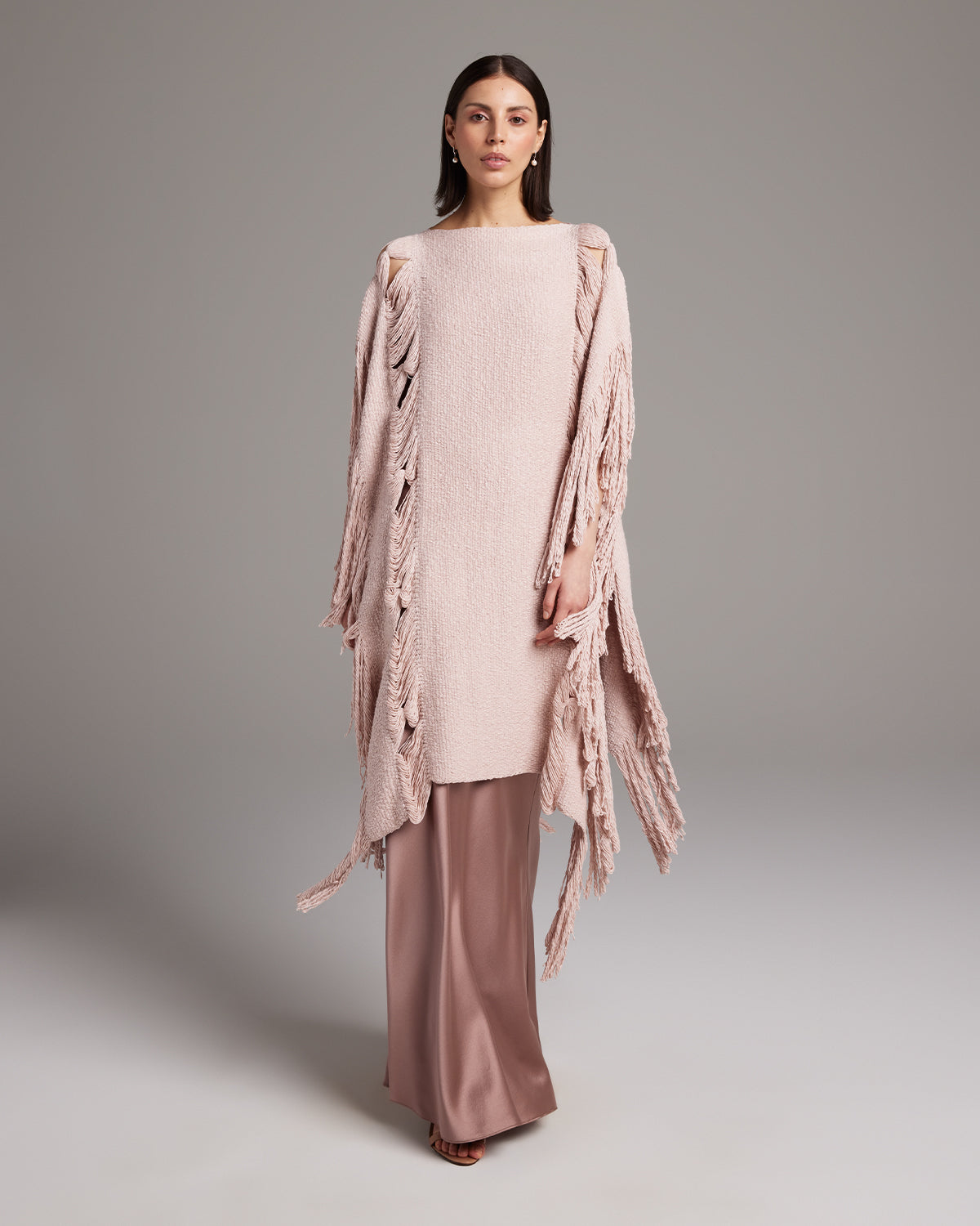 Model wearing a Lace Fringe Manta in rose color, styled with matching pants.