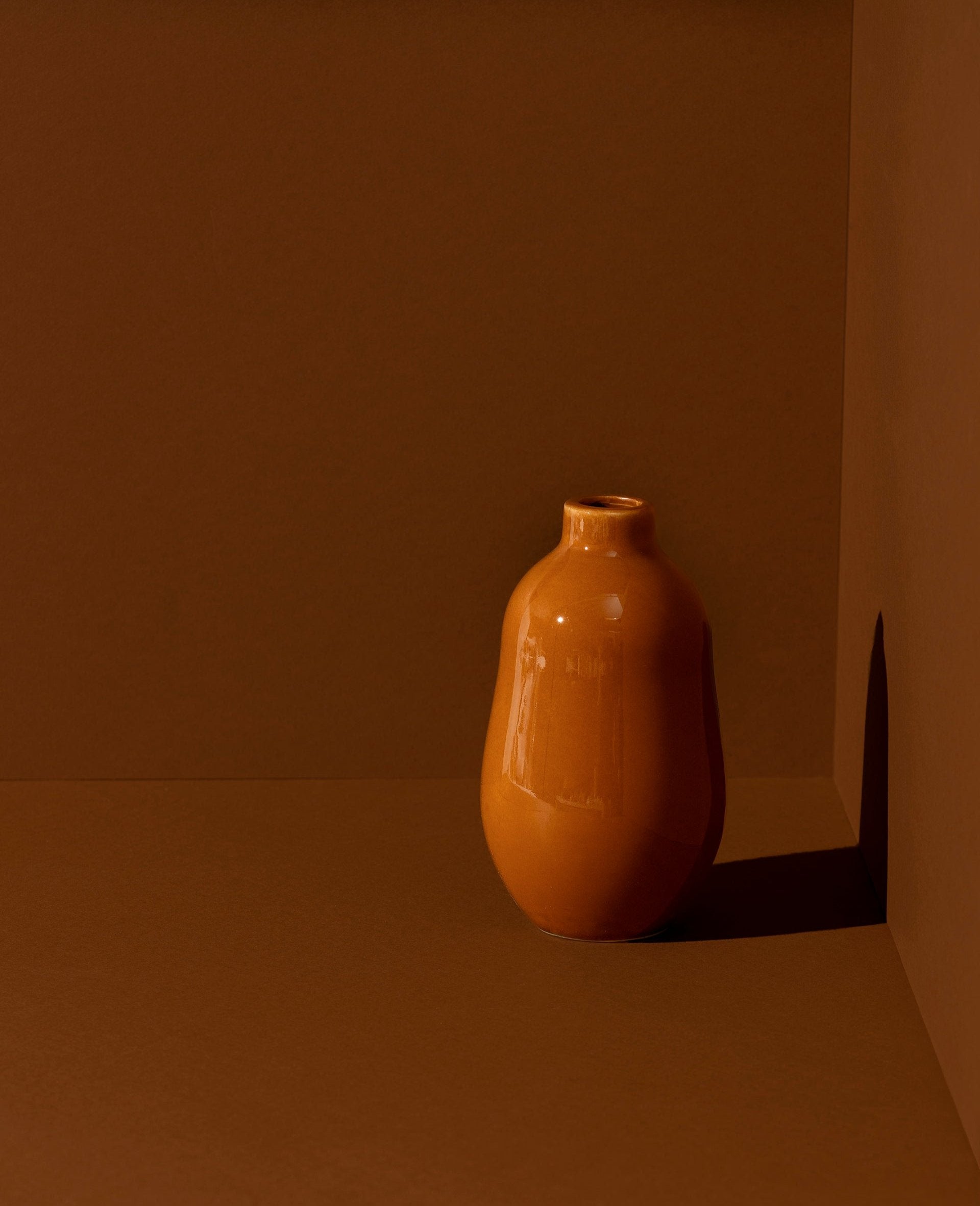 A white stoneware vase with a minimalistic design, placed on a surface and containing a green plant, showcasing its use as a decorative table accessory.