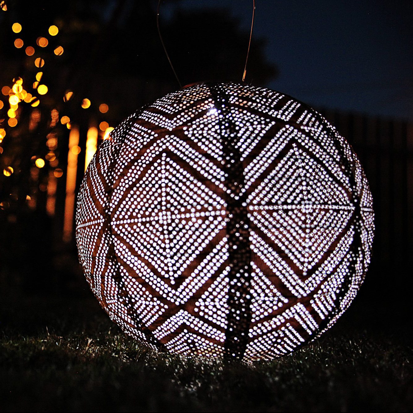 Soji Stella Market 12" Tyvek Solar Lantern glowing at night in backyard