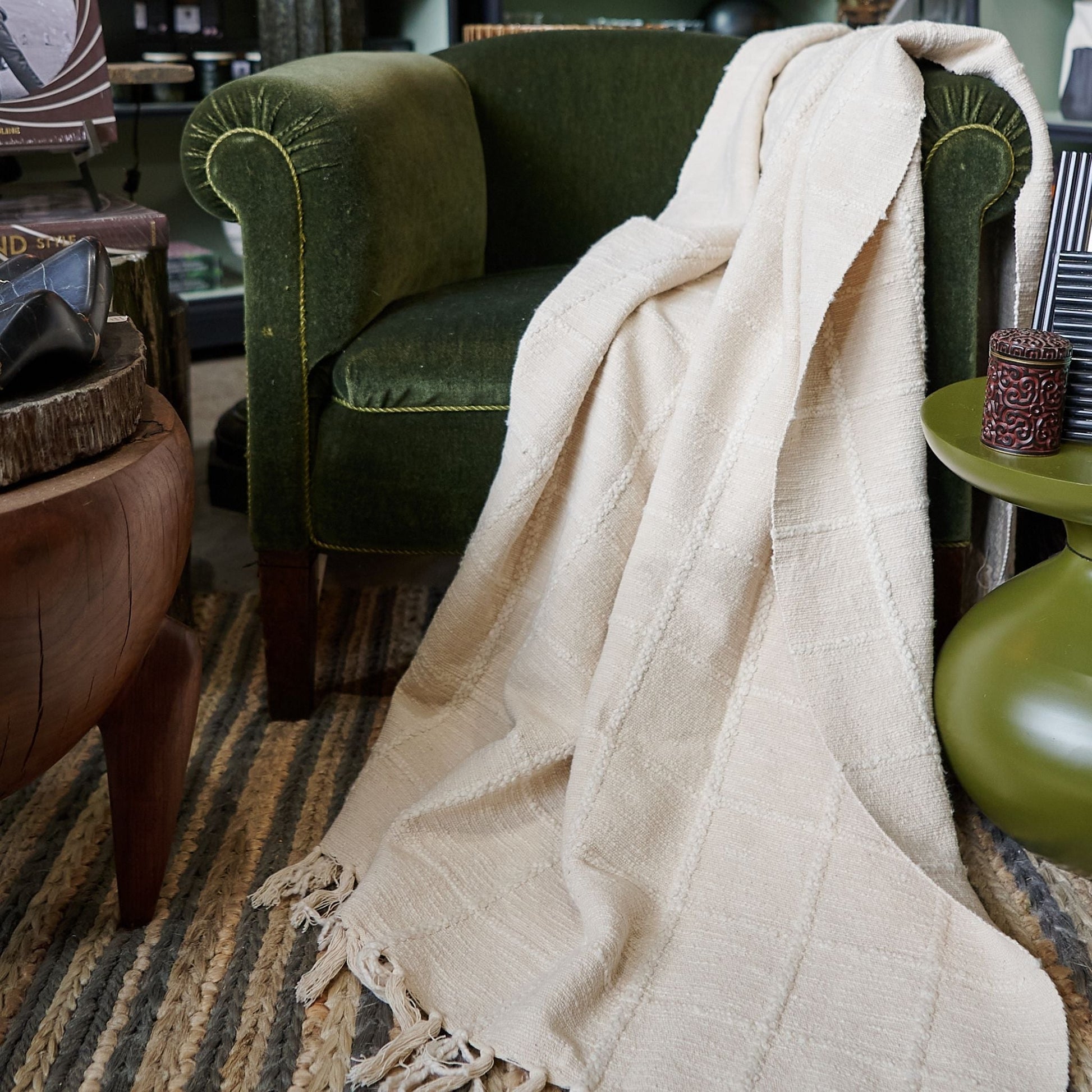 Sea Shell White Textured Checks Handloom Throw draped over a green chair, showcasing its subtle texture and design.