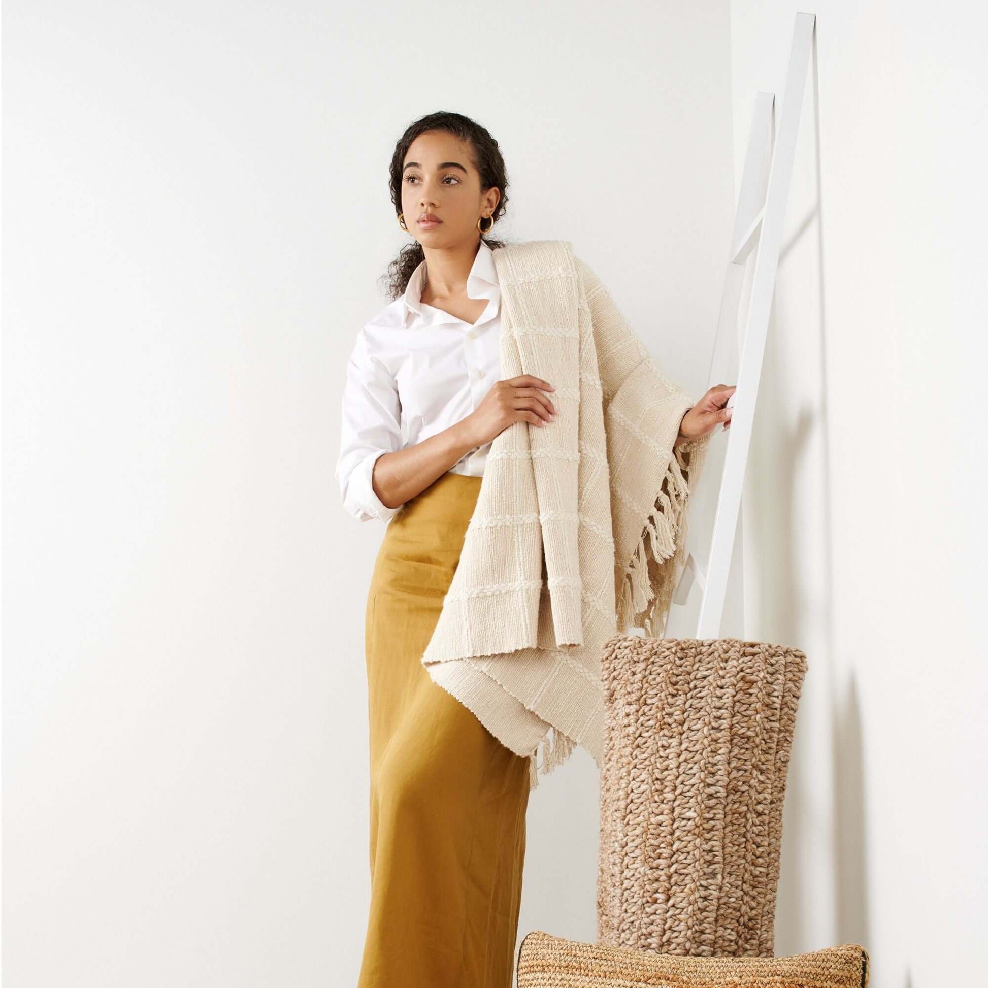 A woman draped in the Sea Shell White Textured Checks Handloom Throw, showcasing its exquisite texture and design.