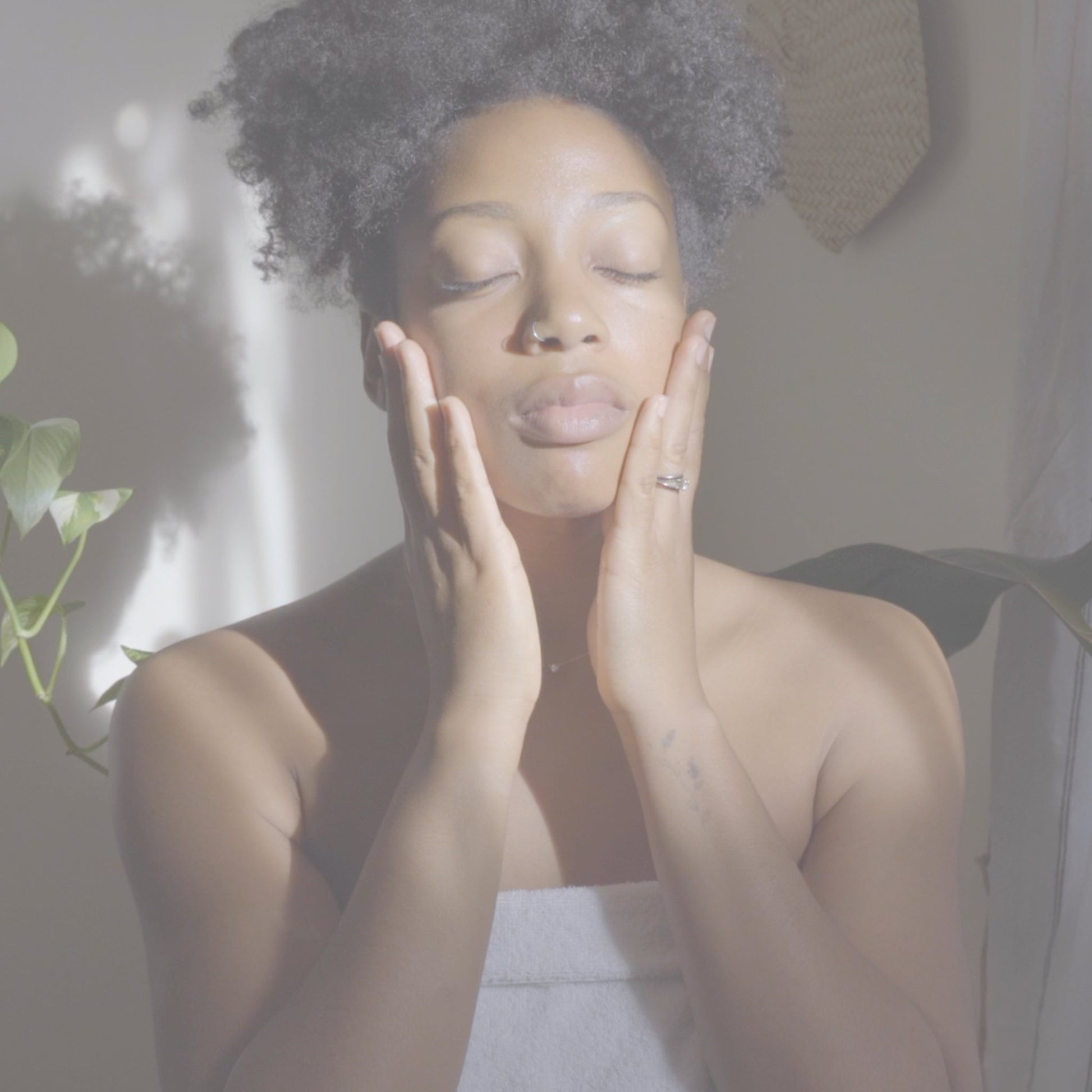 Video of woman gently applying facial serum to her skin, pressing product into her cheeks as part of an evening skincare routine.