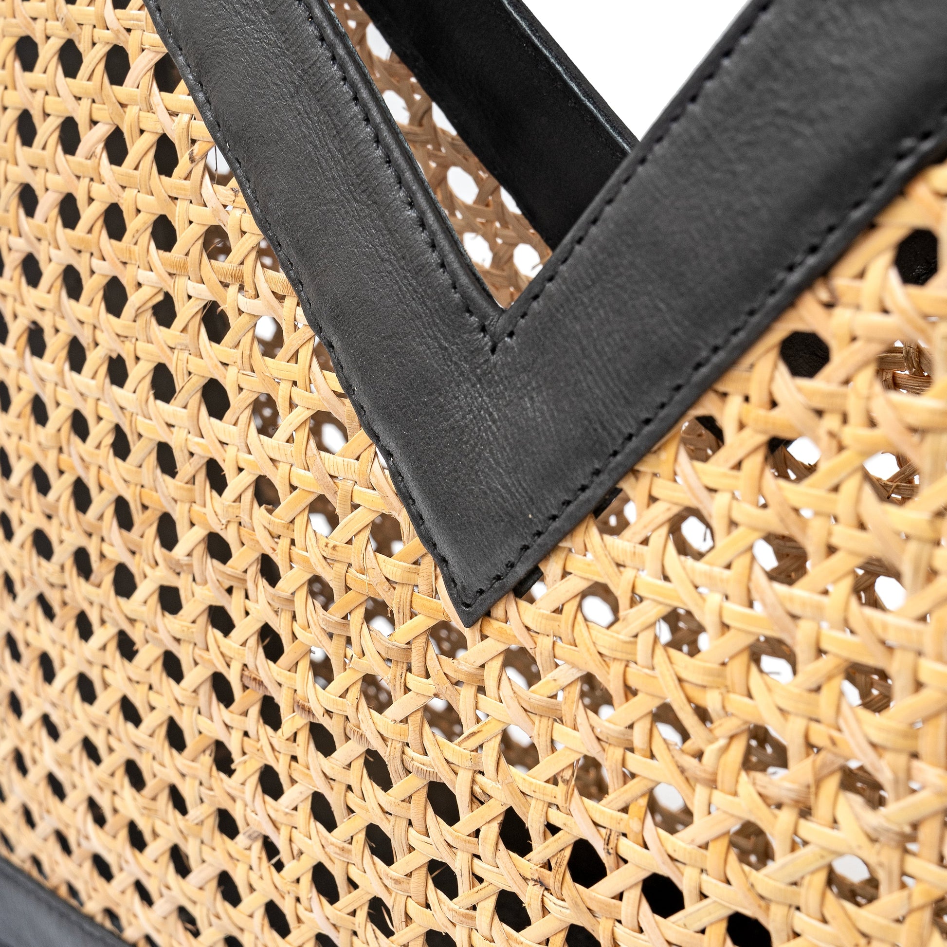 Detail view black leather trim and open weave rattan cane webbing top handle tote basket handbag