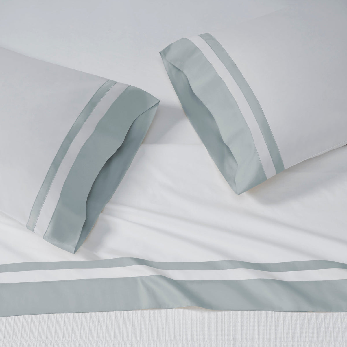 AKP-541-2040_2|White 100% cotton sateen sheet set, including two pillowcases and a flat sheet, each featuring wide light blue and white striped borders.