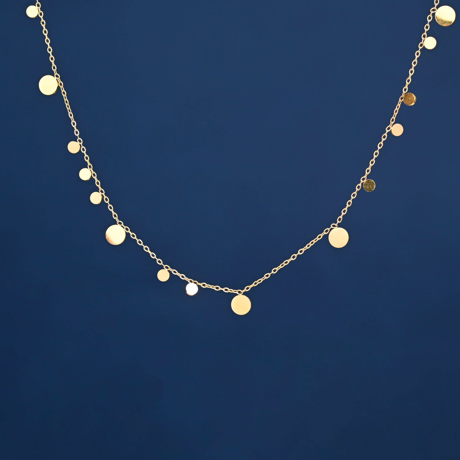 Photo of gold necklace with blue background, gold circles on necklace, ideas for Mother's day
