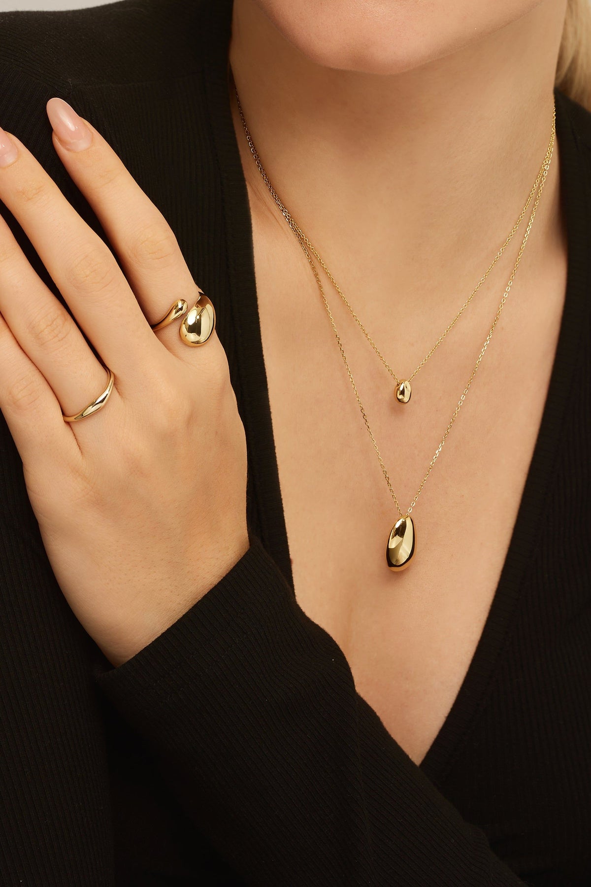 Gold-toned Harmony Pebble Pendant Necklace with layered necklaces and rings