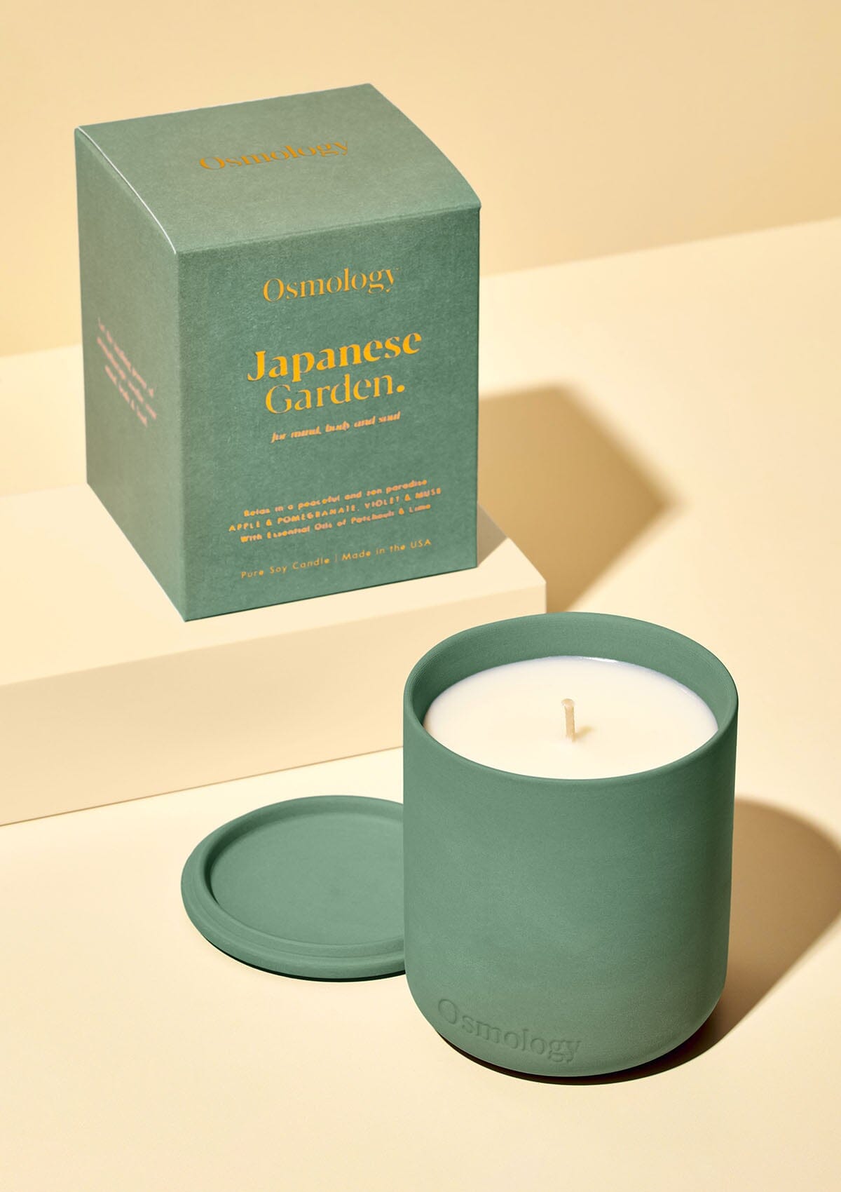 green ceramic candle with lid displayed next to product packaging