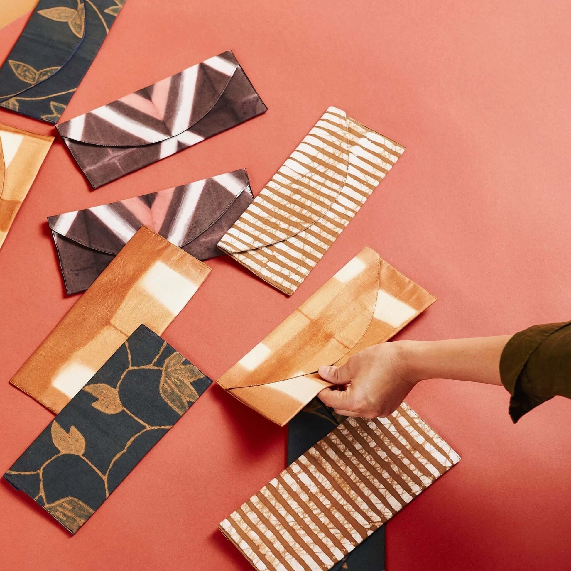 Tisa Artisanal Pouch In Black Pink Triangle Print arranged on a colorful surface.