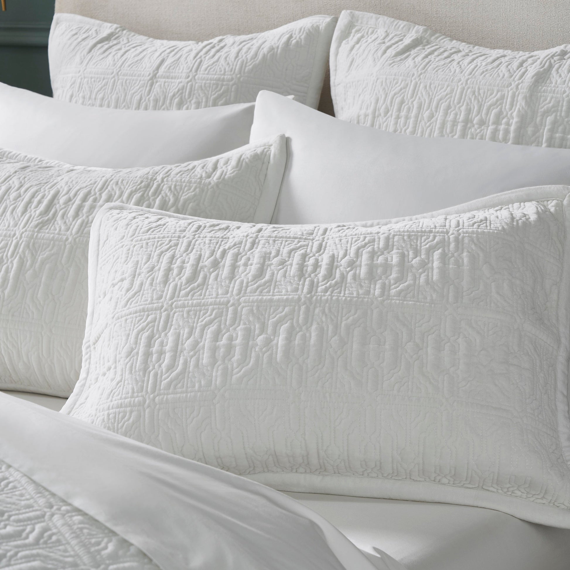 KS-331-DUP-X_1|Collection of white quilted bed shams with geometric patterns, enhancing modern bedroom aesthetic with texture.