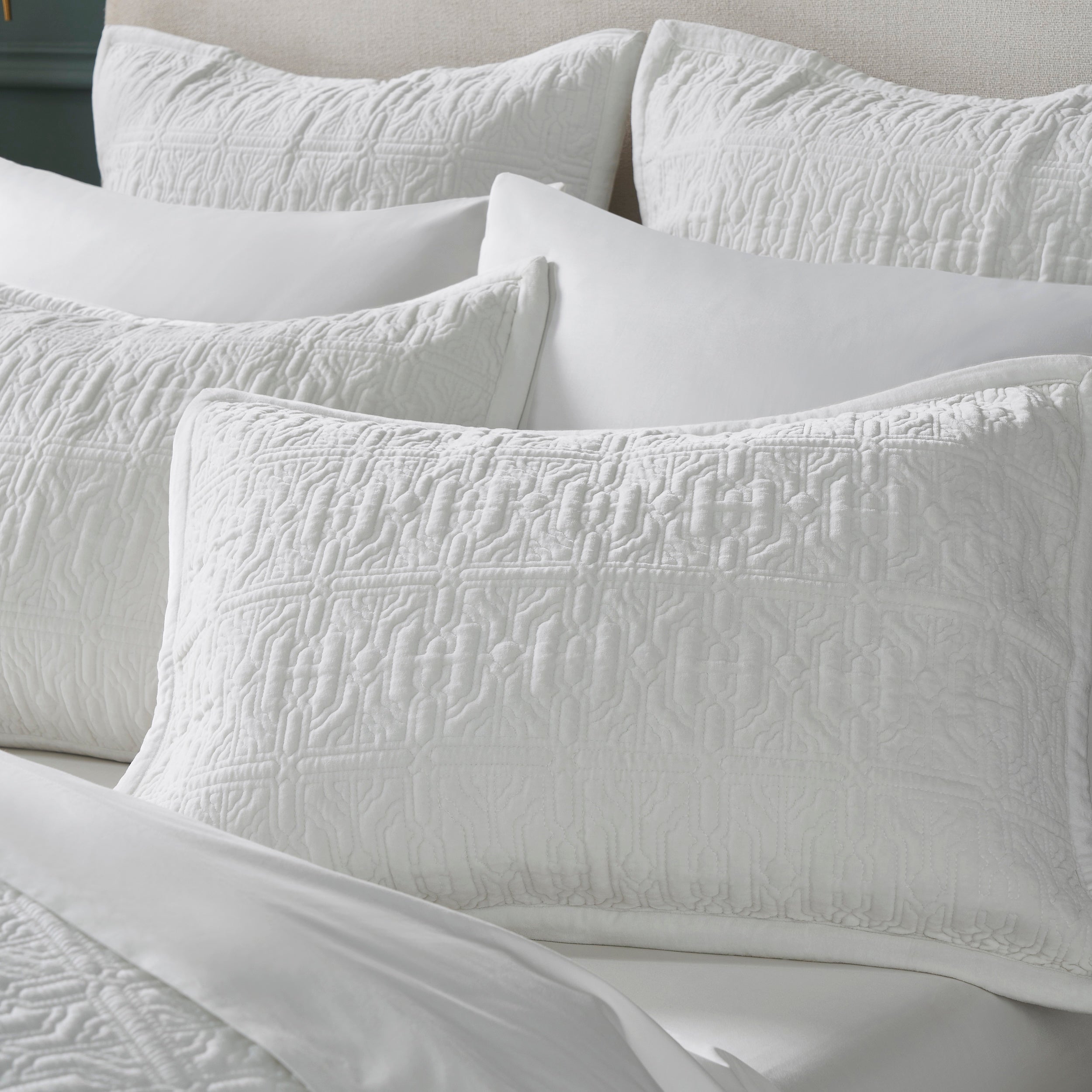 KS-331-DUP-X_1|Collection of white quilted bed shams with geometric patterns, enhancing modern bedroom aesthetic with texture.