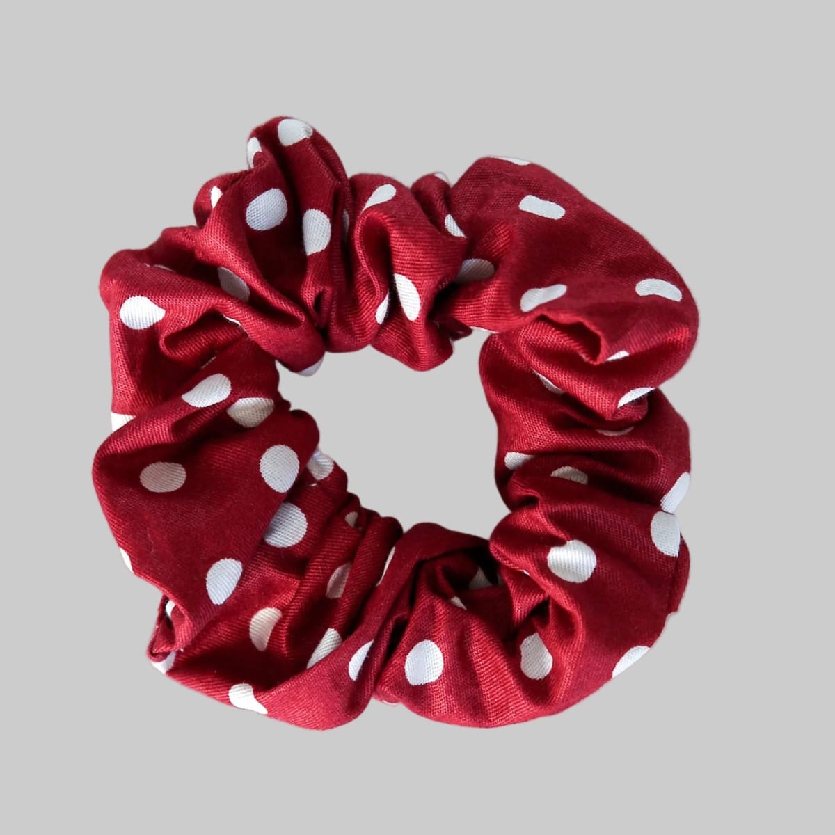 Red scrunchie with white polka dots on a gray background