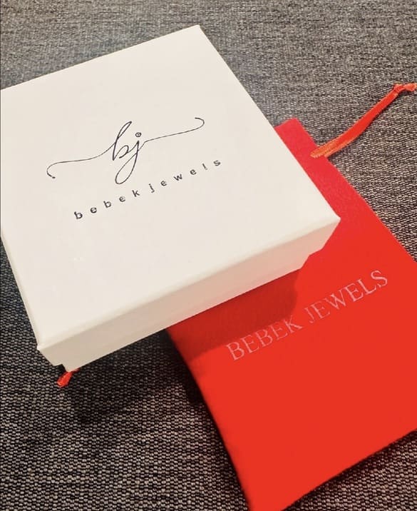 White jewelry box and red case with 'Bebek Jewels' branding on a textured surface.