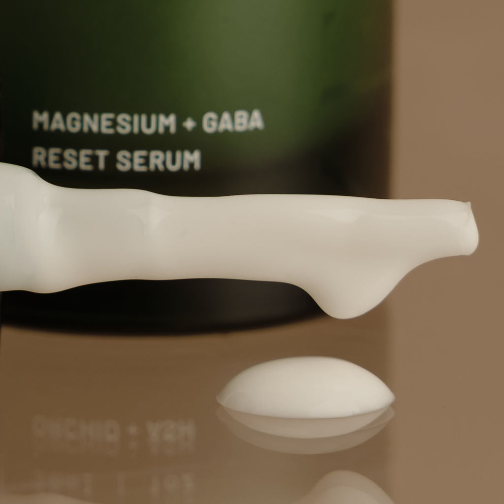 Serum bottle labeled 'Magnesium + GABA Reset Serum' on a reflective surface.