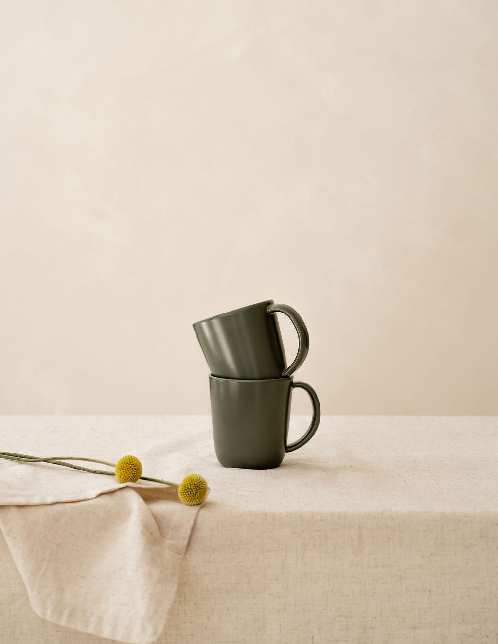 Stacked Moss green ceramic mugs by Hamkke Home on a neutral linen table.