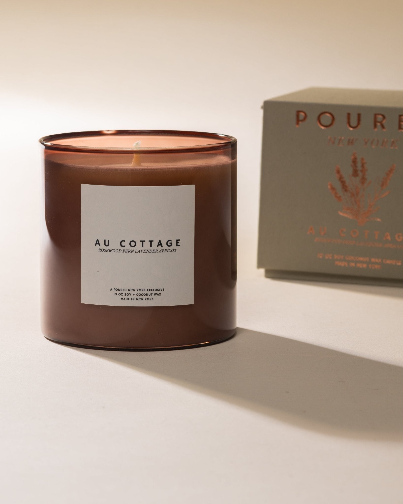 Poured New York 'Au Cottage' nude colored glass candle with grey candle box and lavender decal on a neutral background
