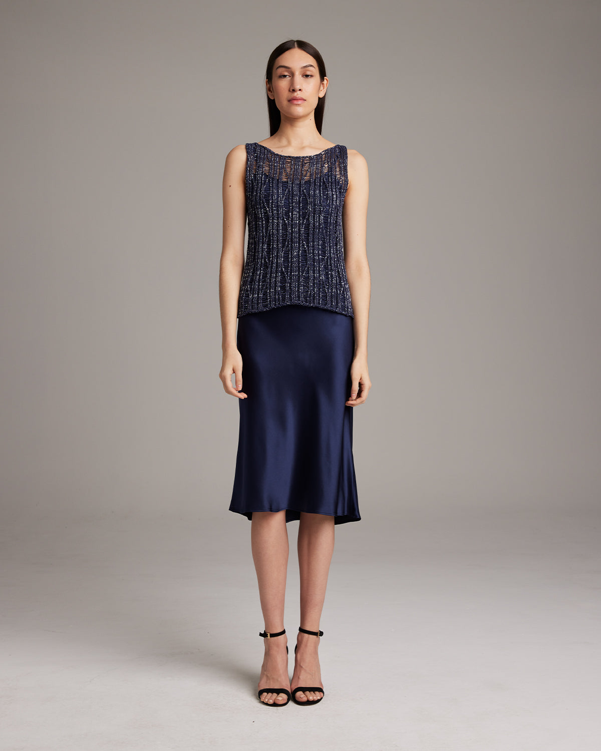 Model wearing a navy Lace Knit Tank with a satin skirt and heels.