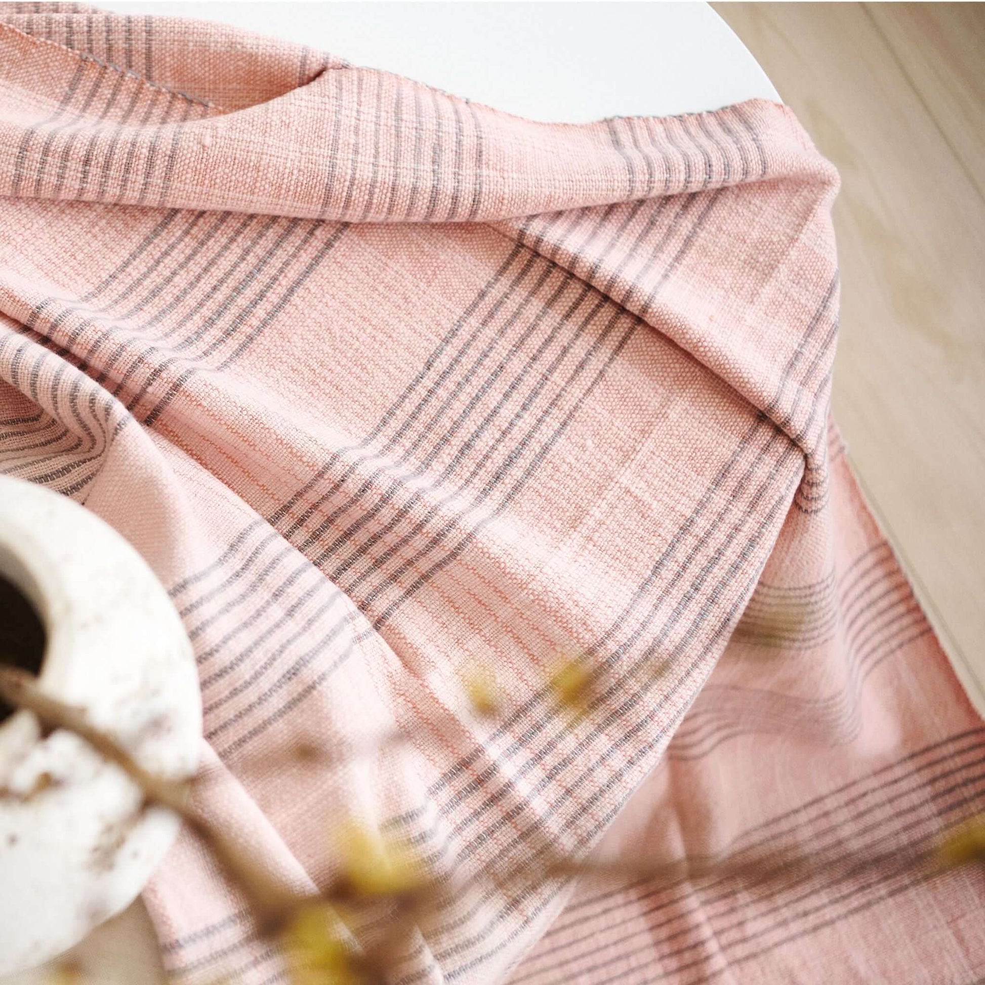 Silica Rose In Shades of Salmon Pink Gray Stripes Pattern Soft Handwoven Merino Throw draped over a table.
