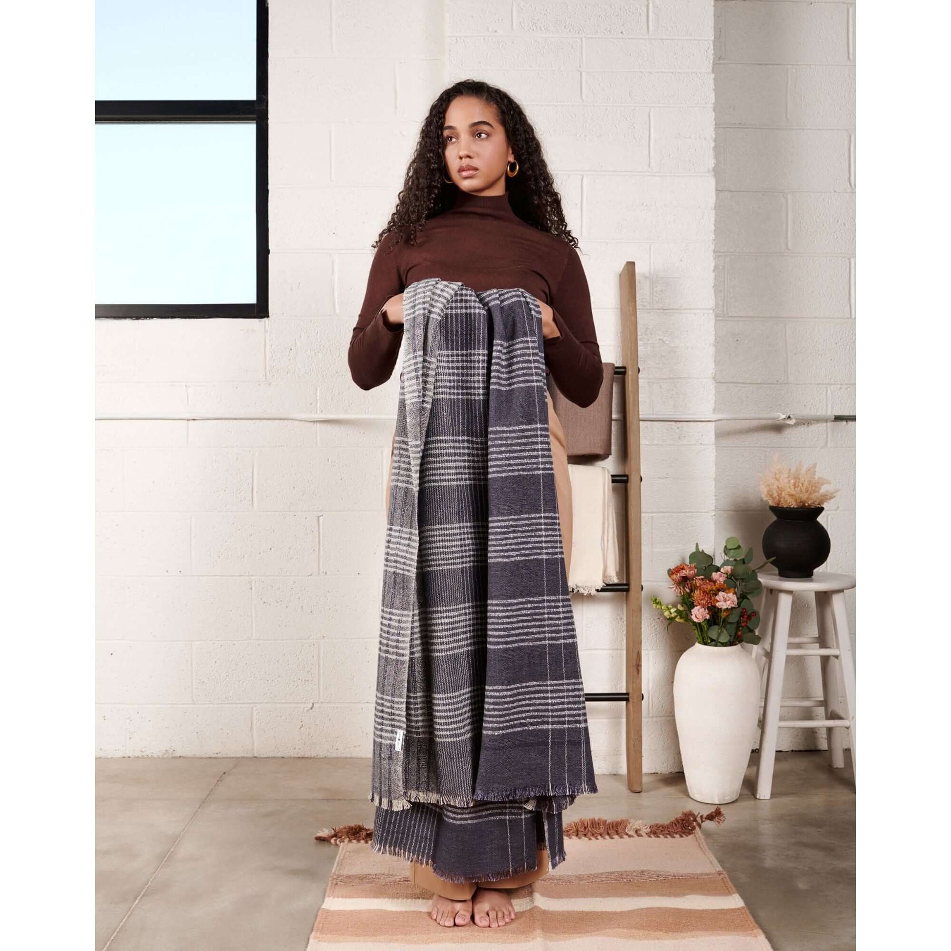 Alloy Dark Blue Stripes Pattern Soft Merino Linen Handloom Throw displayed by a model in a modern indoor setting.