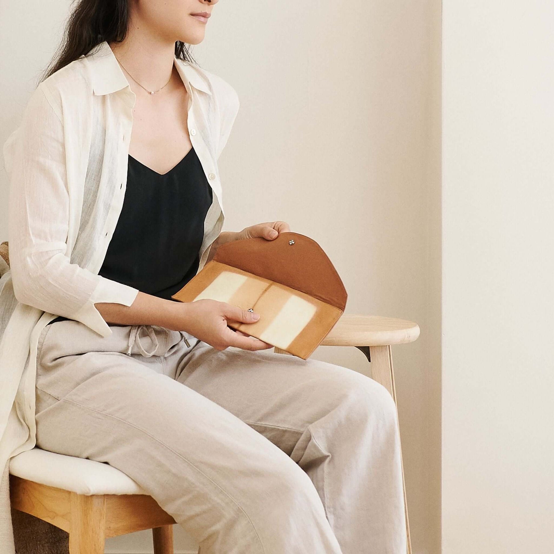 Melo Gold Mulberry Silk Shibori Hand Crafted Envelope Pouch held by a woman wearing casual clothing.