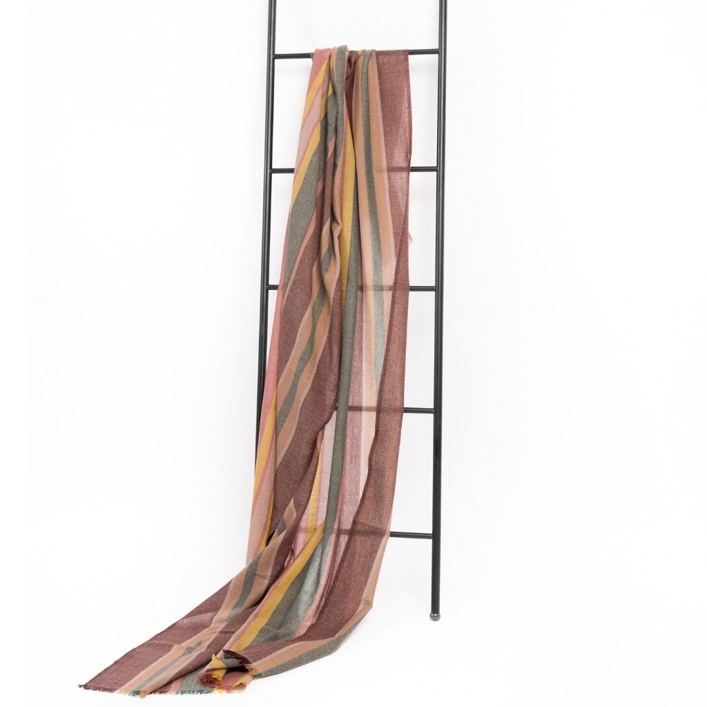 Barque Clay Modern Artisan Striped Soft Merino Handwoven Scarf displayed on a black ladder, showcasing its elegant colors.