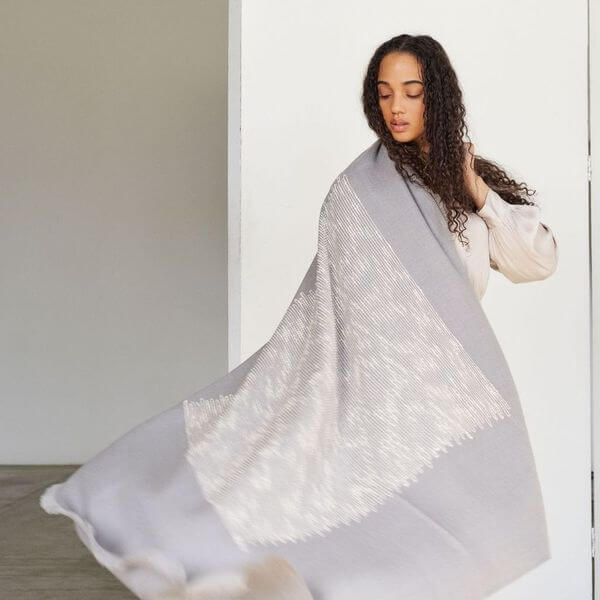 Model draped in a Flo Gray Textured Handloom Merino Throw showcasing its luxurious design and craftsmanship.