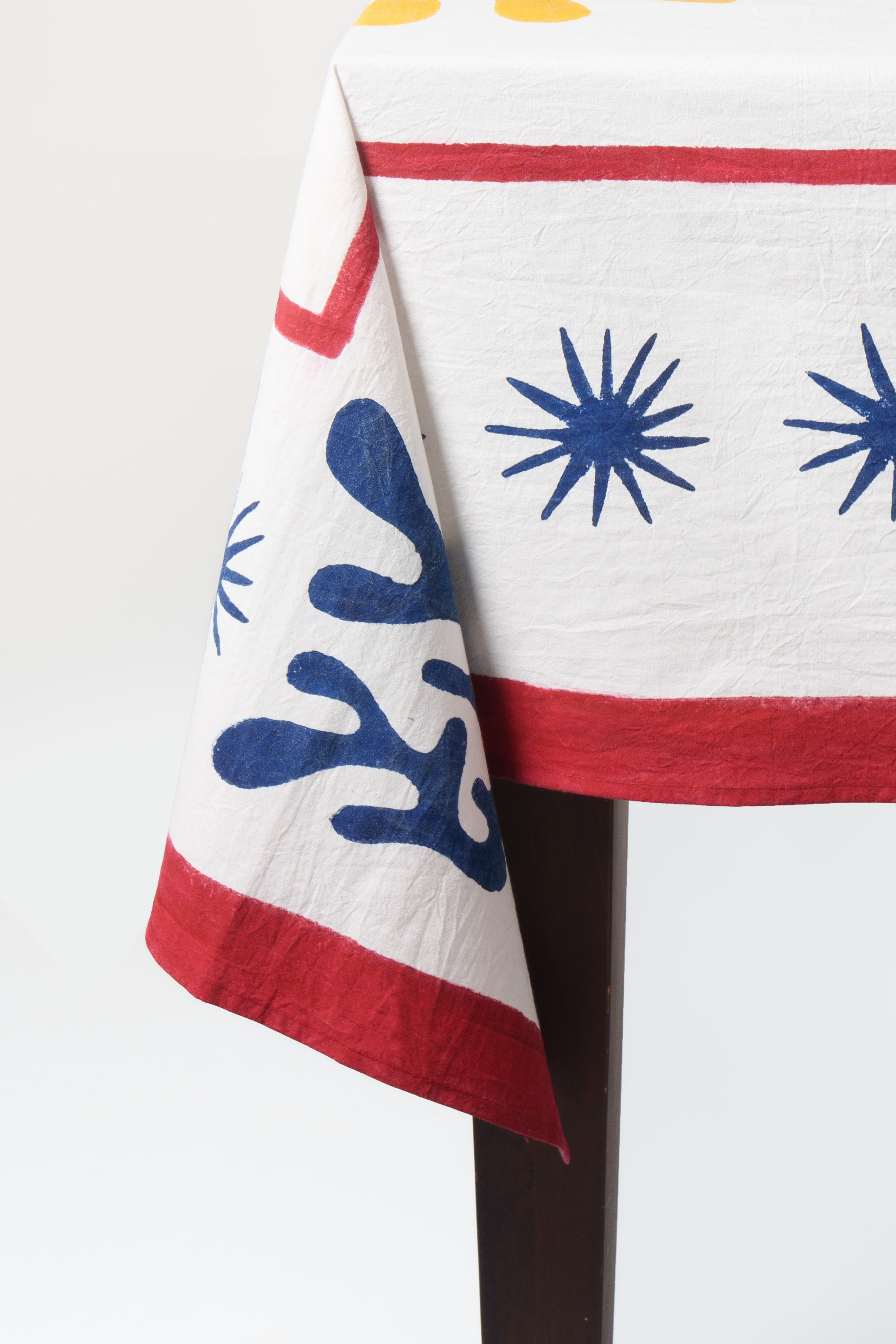 Celestial Matisse Blockprint tablecloth close-up showing blue starbursts and red border