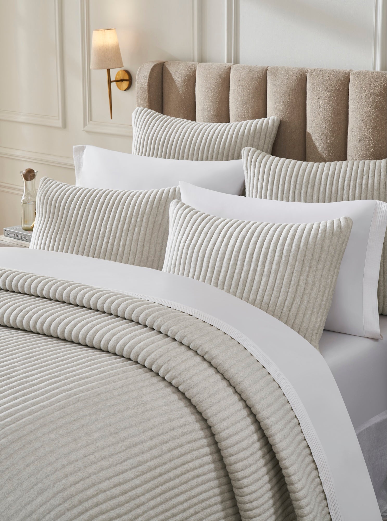 QT-375-9496_3|Close-up of ribbed ivory quilt and pillow shams on a bed, highlighting soft texture and sophisticated design.
